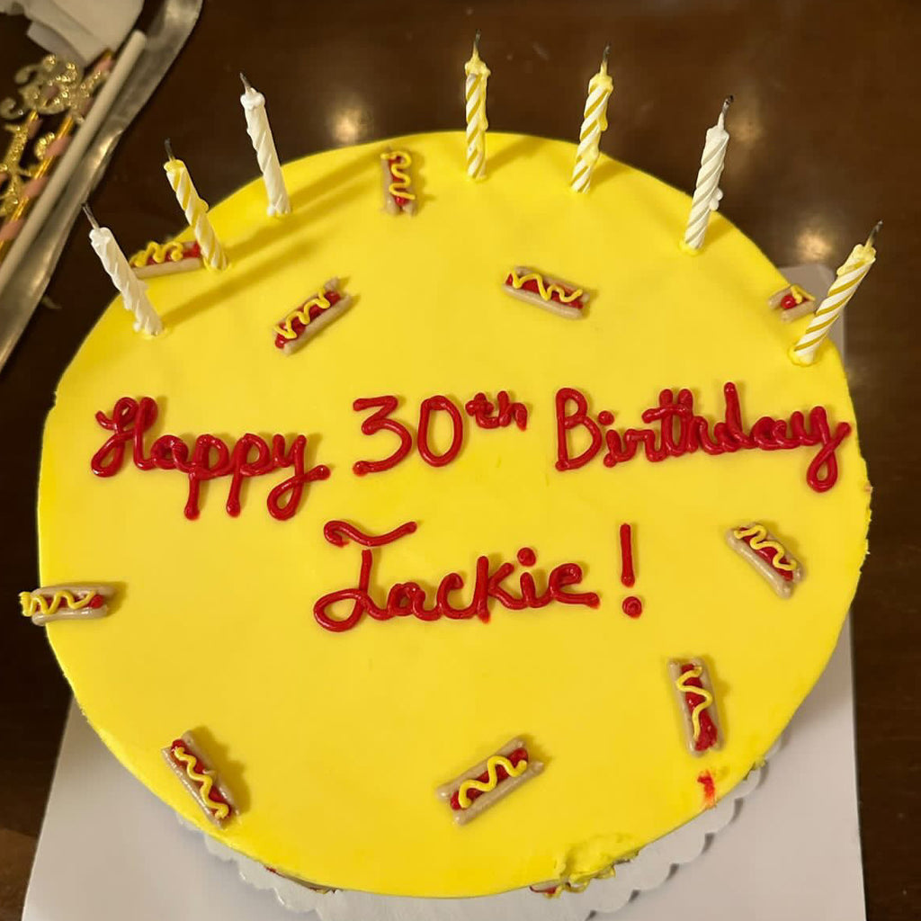 A yellow cake decorated with mini hot dogs 