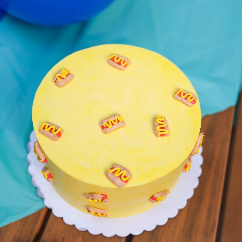 A yellow cake decorated with mini hot dogs 