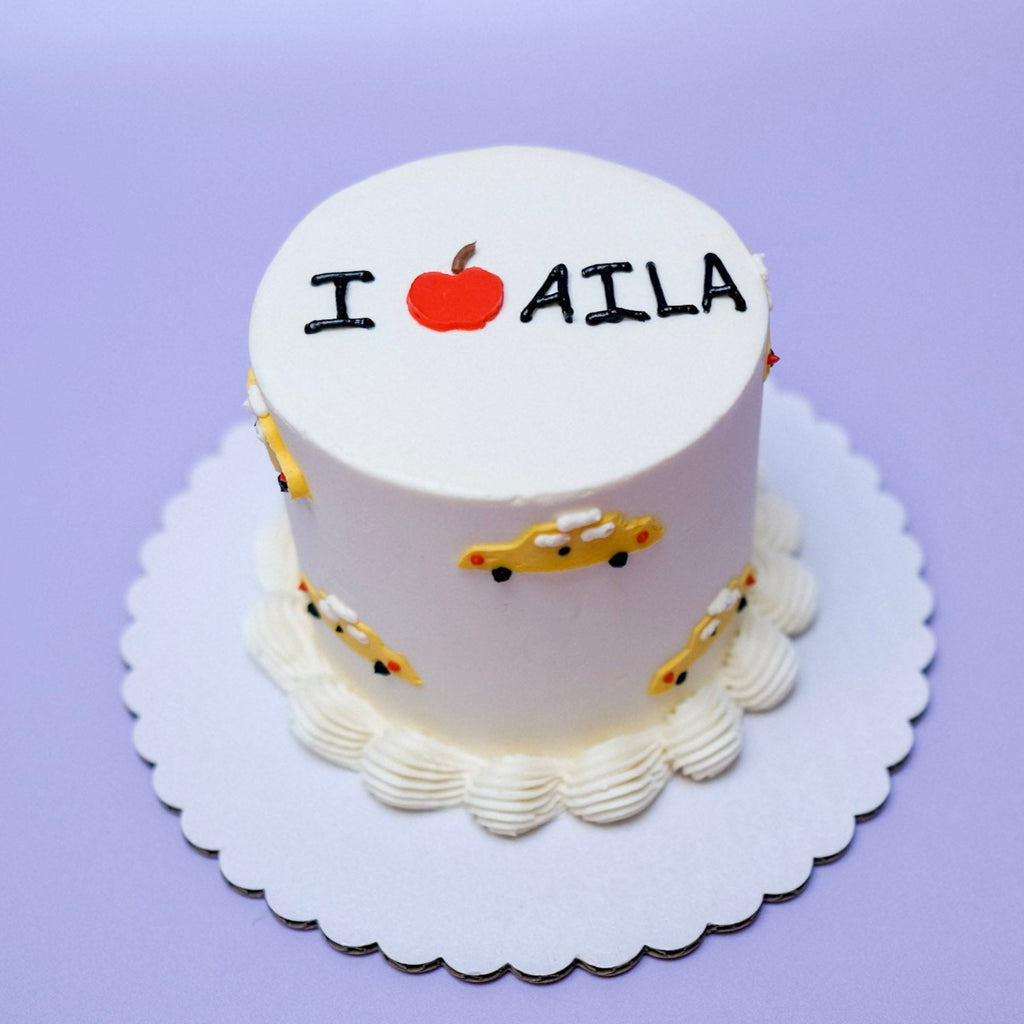 A white cake decorated with little yellow taxi cabs. 