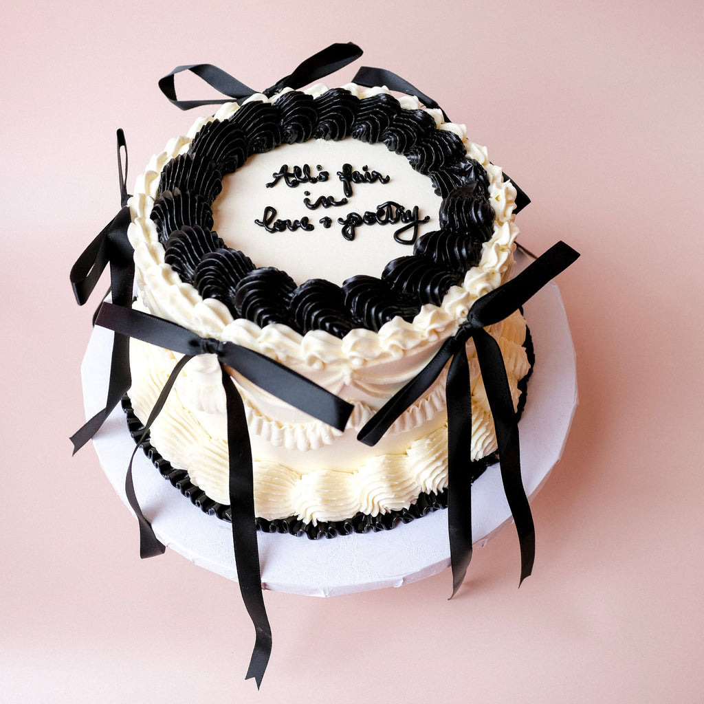 White and black ornate cake with black ribbons