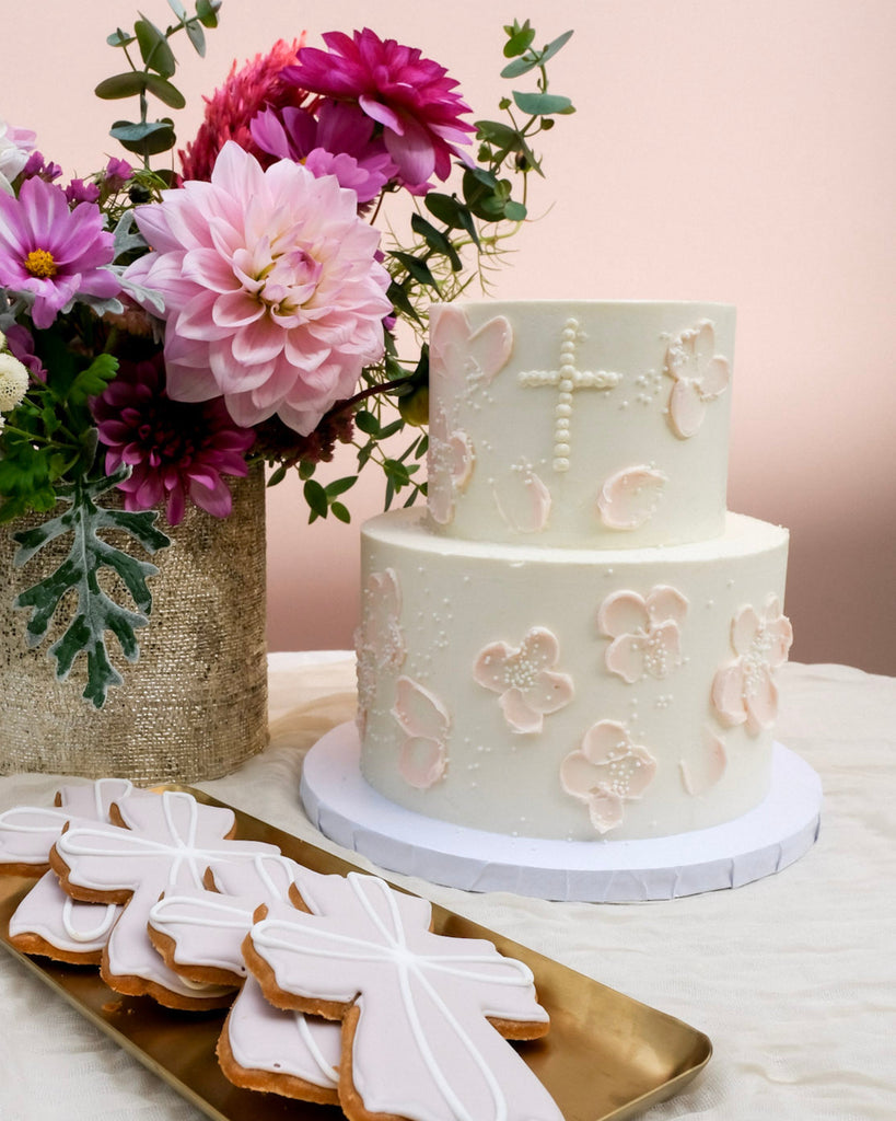 double tired pink floral baptism cake with white sprinkles with pink cross cookies