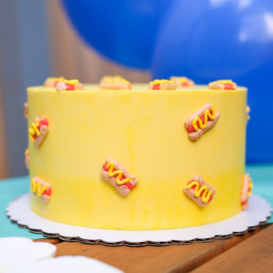 A yellow cake decorated with mini hot dogs 