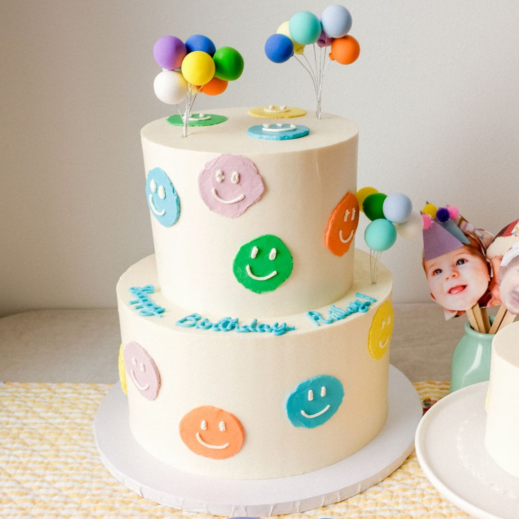 A double tiered colorful smiley face cake