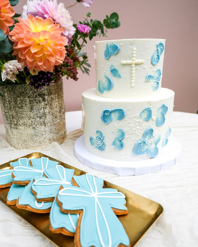double tired blue floral baptism cake with white sprinkles with blue cross cookies 