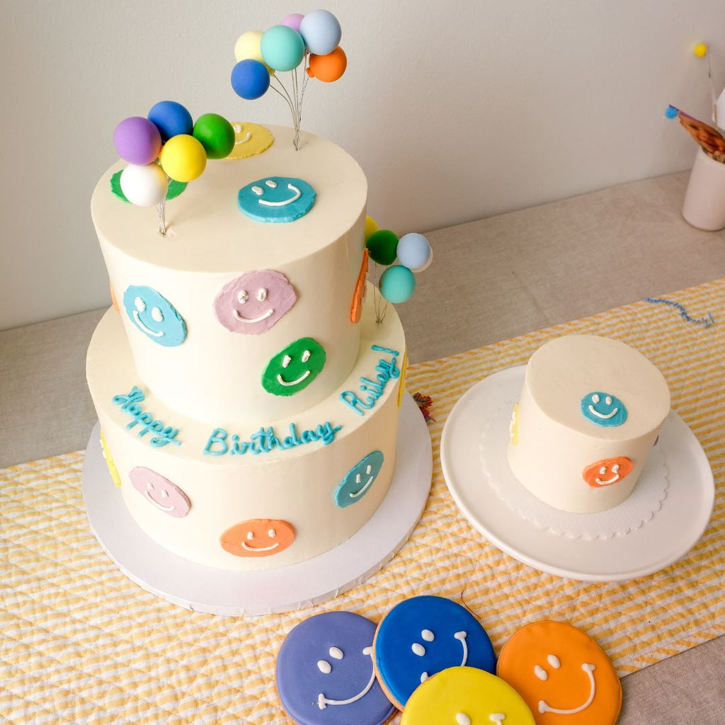 A double tiered colorful smiley face cake