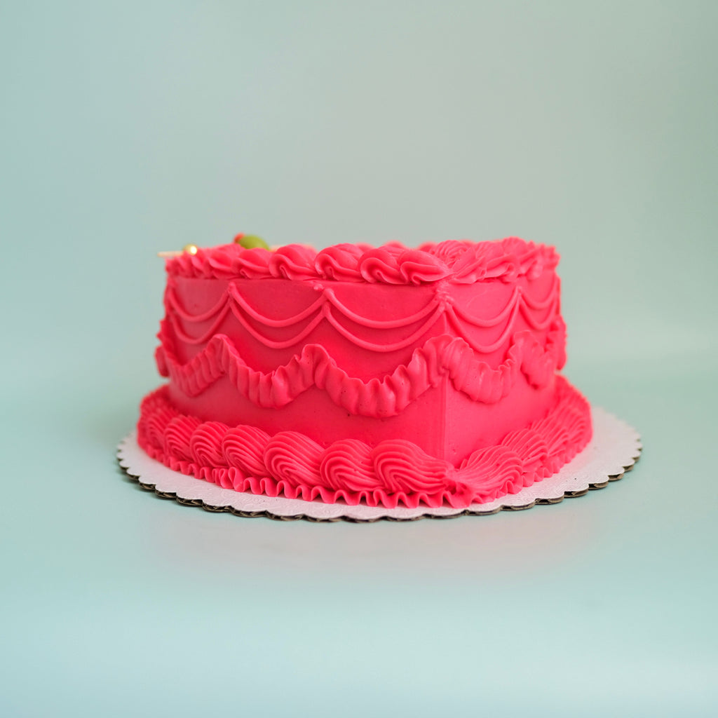 A pink tini bit older heart shaped cake.  The cake has pink ornate piping.