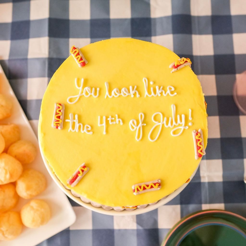 A yellow cake decorated with mini hot dogs 