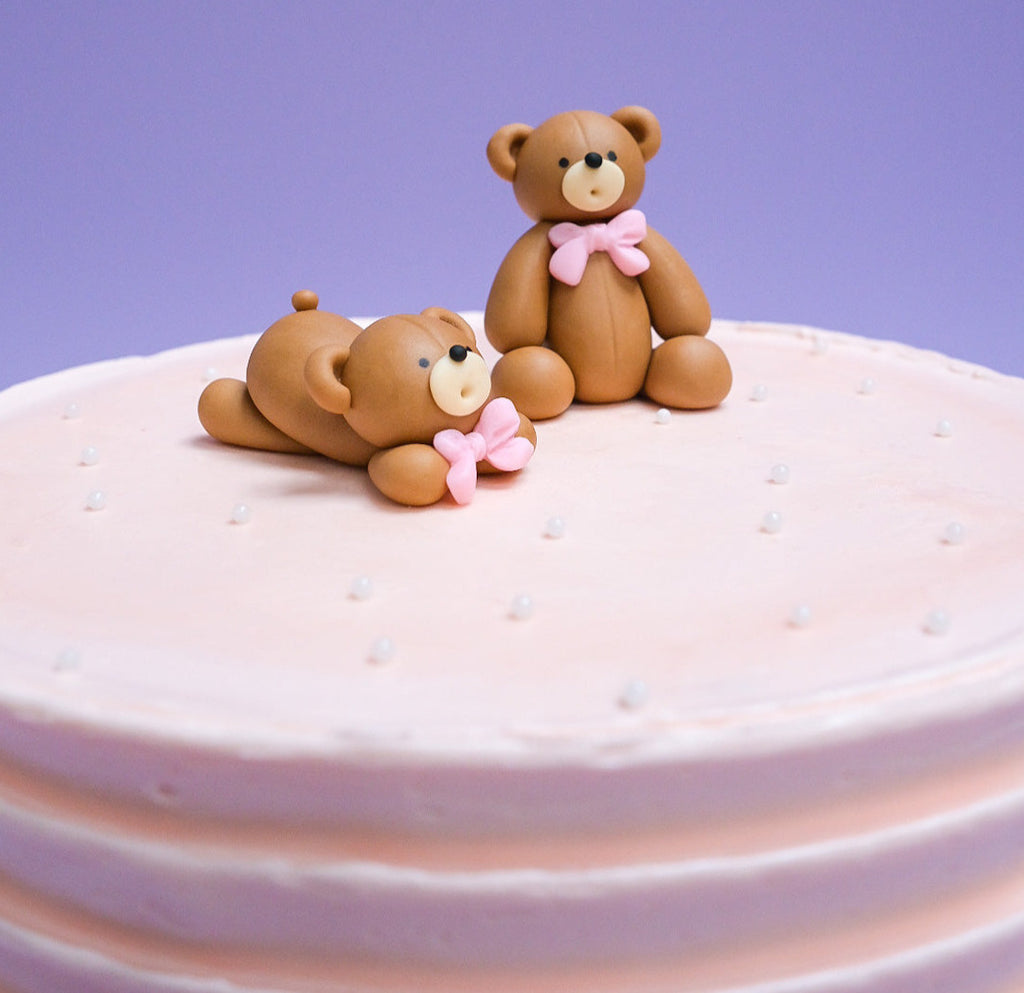 a light pink bear cake with white sprinkles