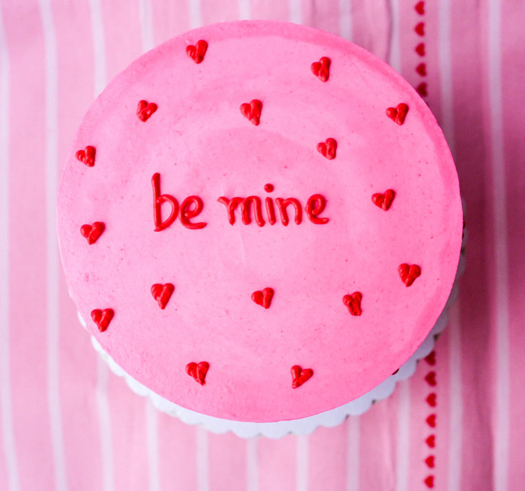 A pink cake with little red hearts