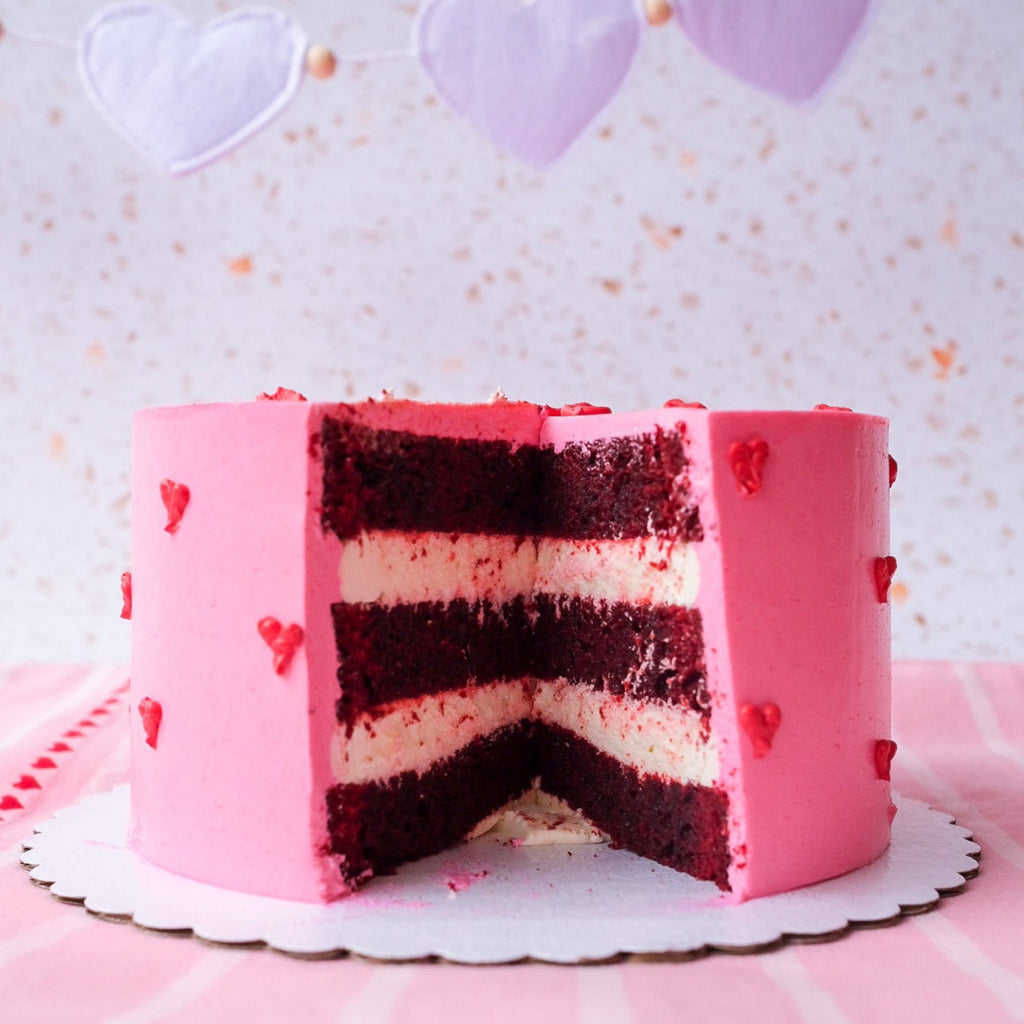 A pink cake with little red hearts