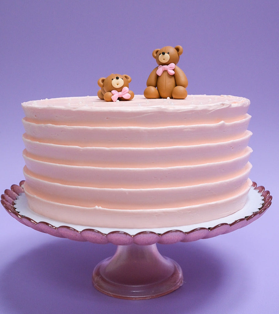 a light pink bear cake with white sprinkles