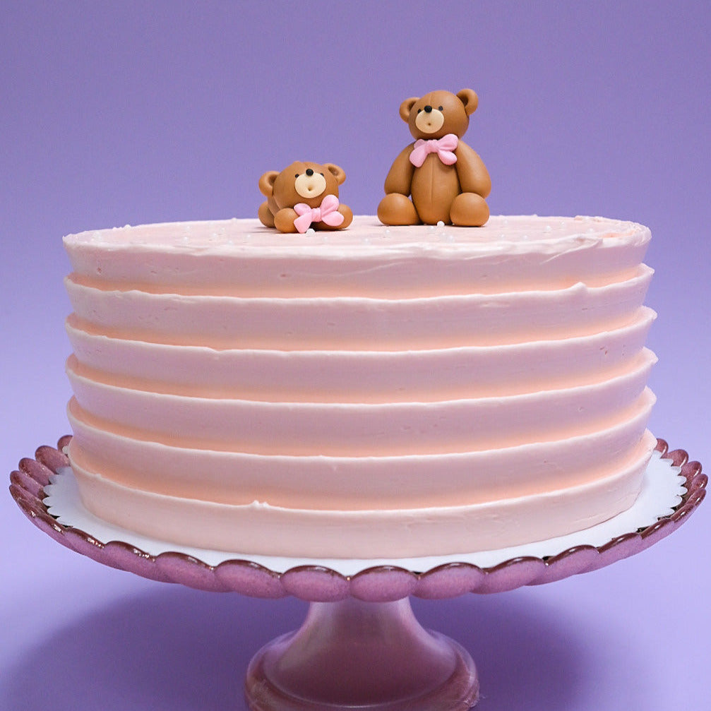 a light pink bear cake with white sprinkles