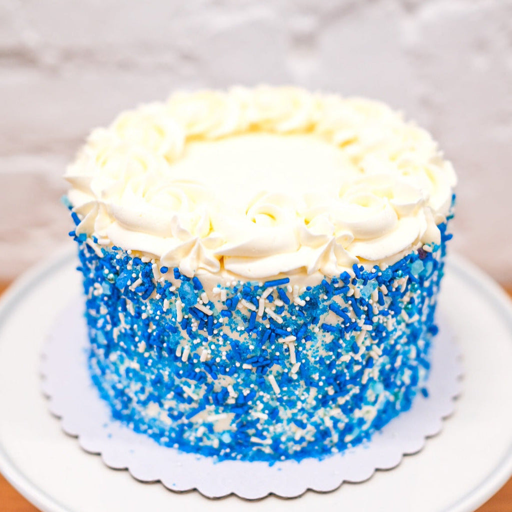 Blue and white classic sprinkle cake with rosettes on top 